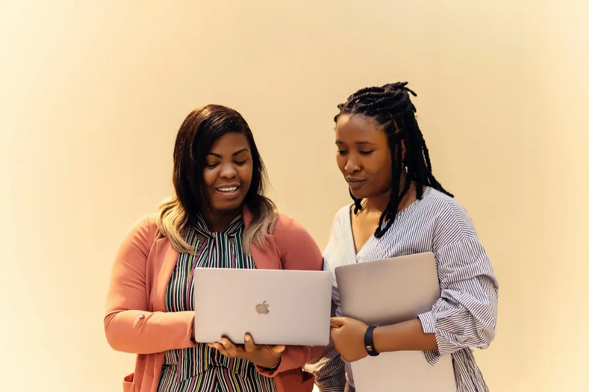 Two colleagues reviewing work on their laptops