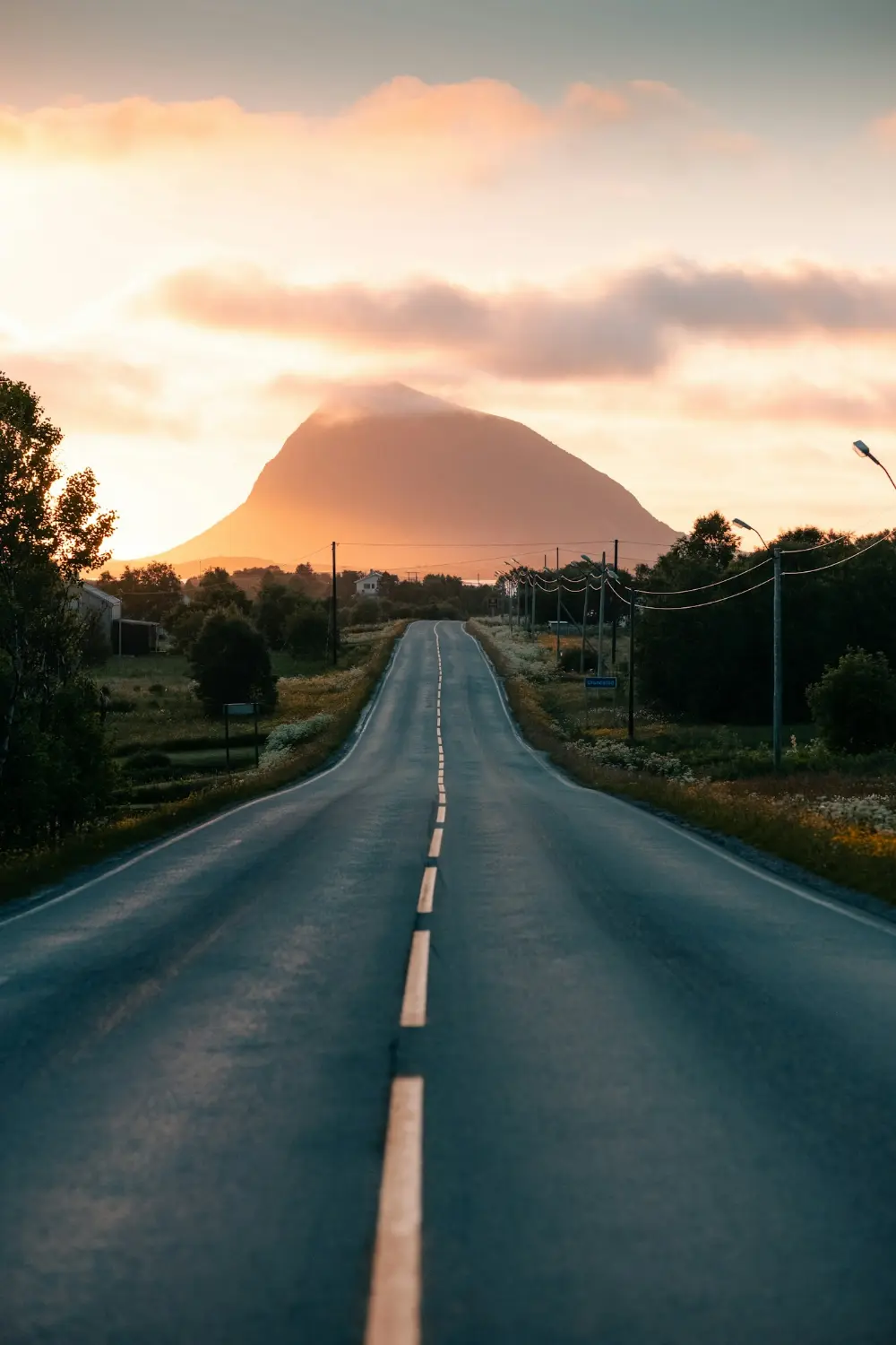 A long road leading towards a mountain at sunset