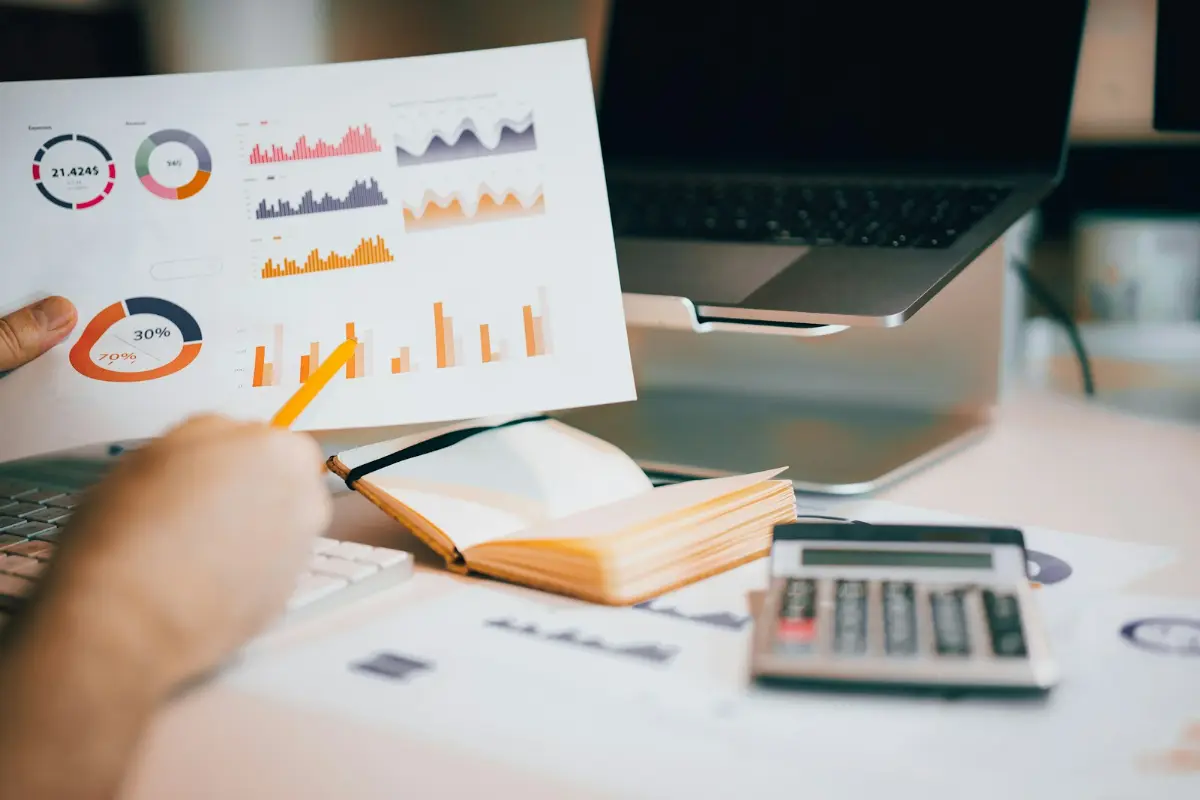 A written investment process reviewed on paper beside a laptop
