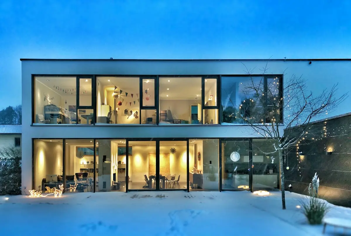 A glass-fronted modern home lit at dusk, illustrative