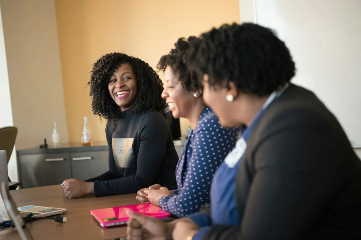 Three women sitting beside wooden table