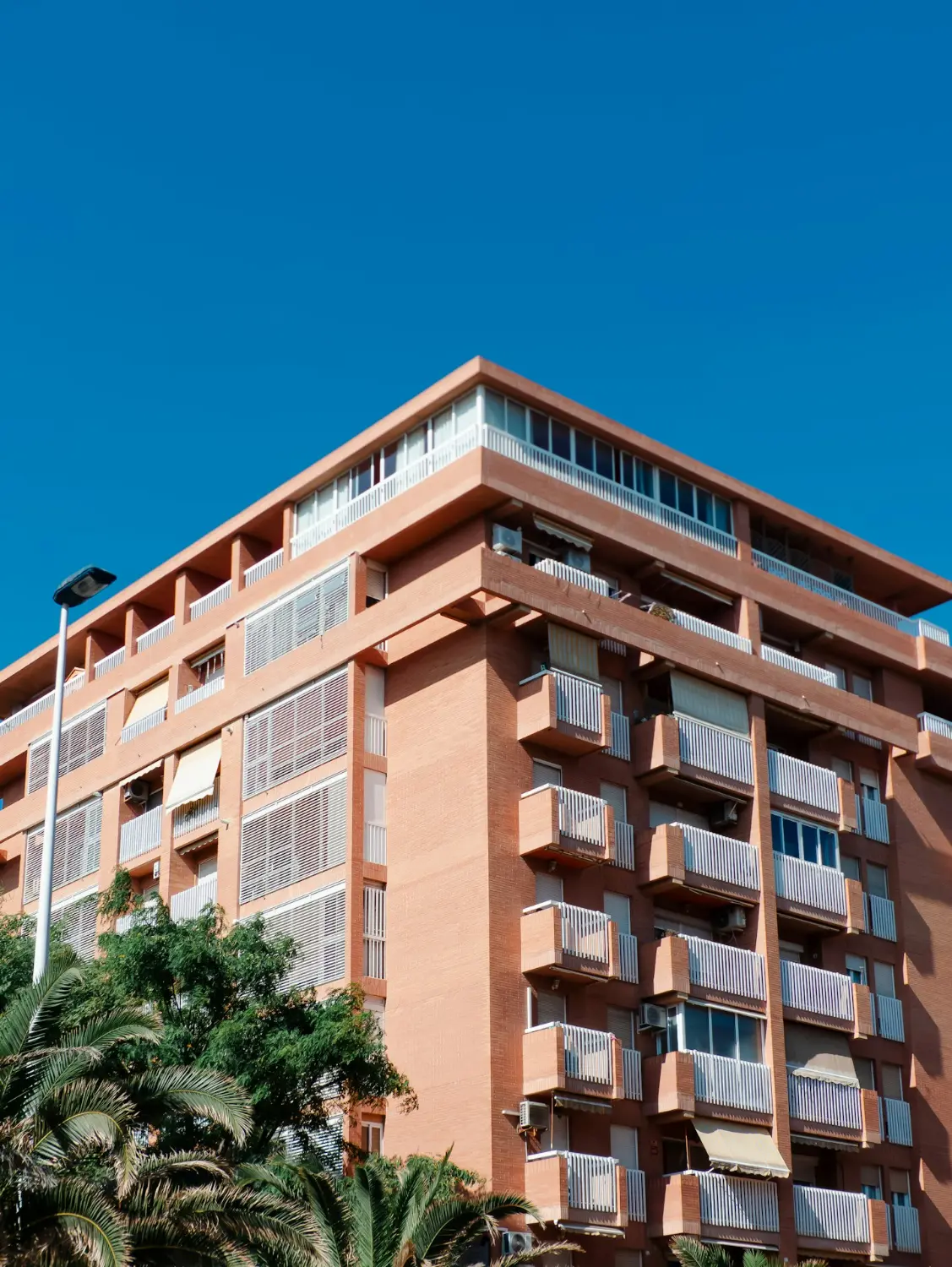 A red-brick residential building with white balconies, illustrative